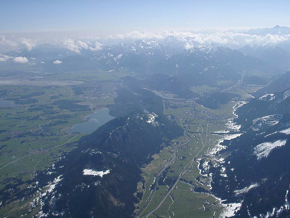 Falkenstein (links die Erhebung) und Vilstal, dahinter der Lechlauf, der Lechdurchbruch bei Füssen und der abgelassene Forrgensee (ganz links hinten)